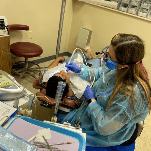 Dental hygienist treating patient in exam chair