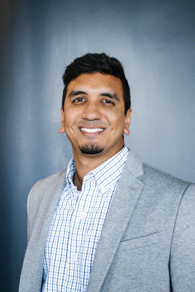 Smiling man in a gray suit jacket.